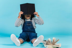 Embarrassed child hiding face behind a book