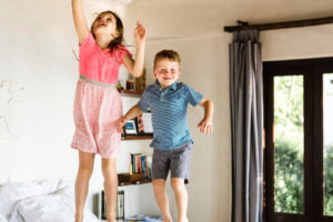 Positive happy children jumping on bed