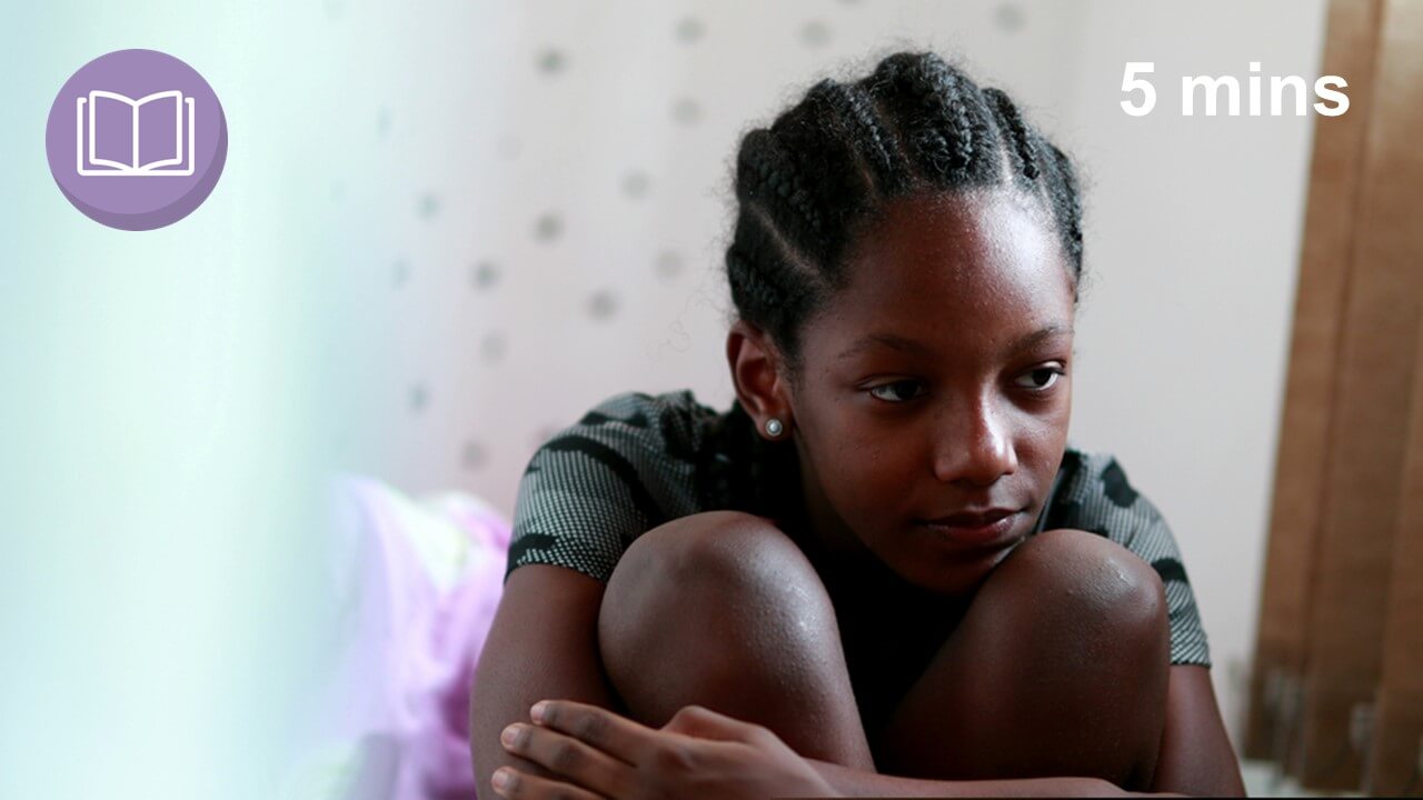 self-harming girl sits on bed hugging herself