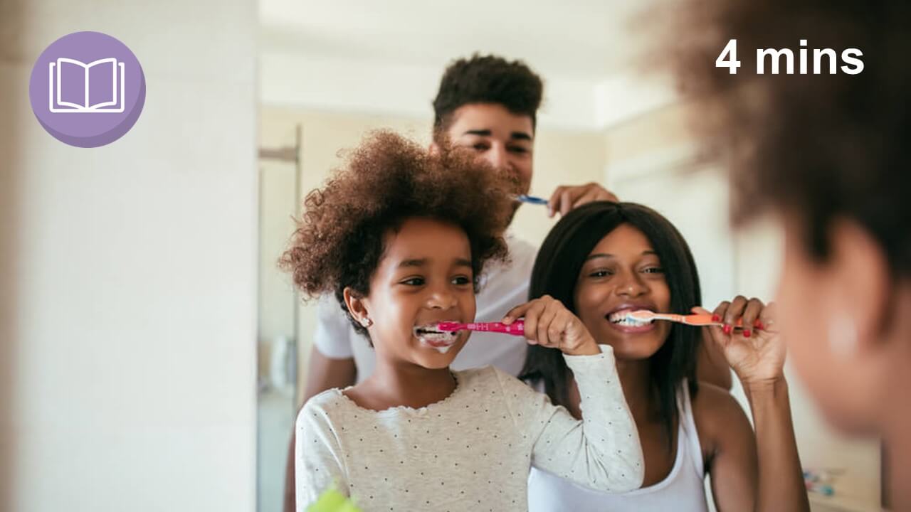 Family brushing their teeth looking in a bathroom mirror